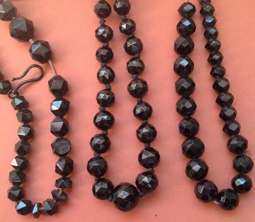 Three faceted bead necklaces, cracked and crazed beads, likely Spanish jet (left), Whitby jet, showing high lustre and sharp facet edges (centre), French jet with chips and abraded facet edges (right). Whitby jet